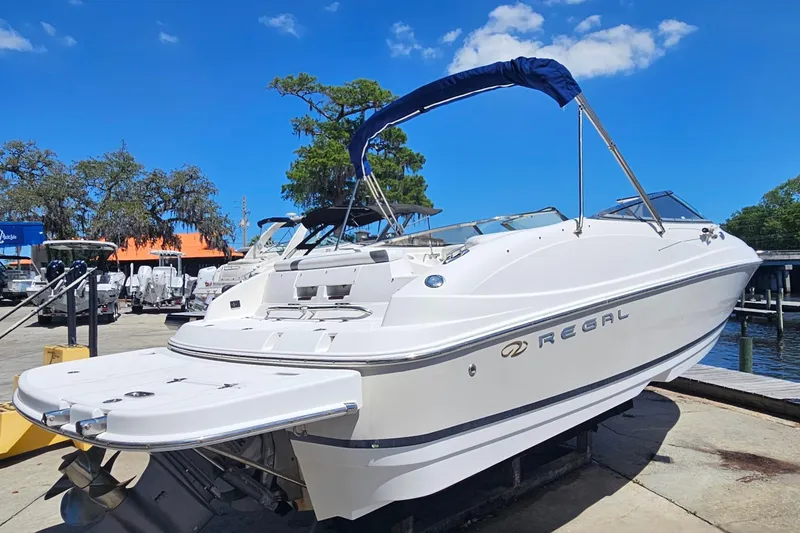 Slide: The Image of 2006 Regal 2400 Bowrider boat on a dock under sunny skies. - 2