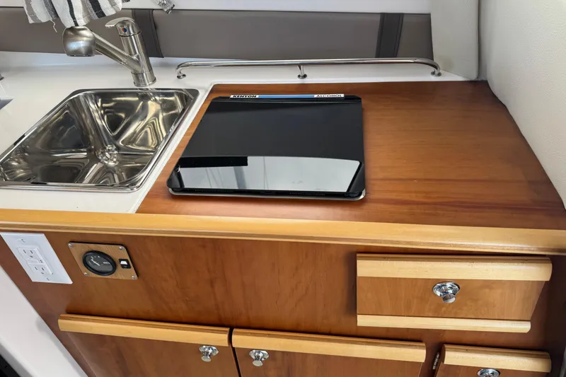 Slide: The Image of 2022 Cutwater boat kitchen with sink, stove, and wooden cabinetry. - 3