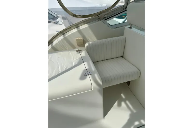 Slide: The Image of White seating area on 2004 Topaz 32 Express boat, featuring cushioned bench and sleek design. - 16