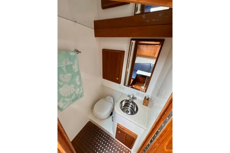 Slide: The Image of 2004 Topaz 32 Express boat bathroom with sink, toilet, mirror, and towel rack. - 27