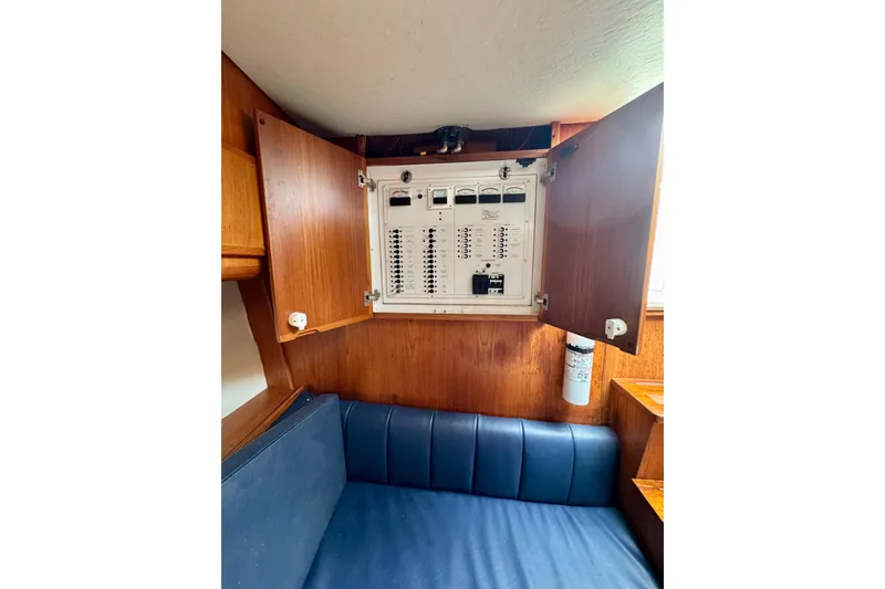 Slide: The Image of Electrical panel inside 2004 Topaz 32 Express boat with wooden cabinetry and blue seating. - 32