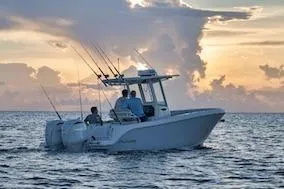 Slide: The Image of 2027 Sailfish 252 CC boat on ocean at sunset, featuring fishing rods and calm waters. - 3