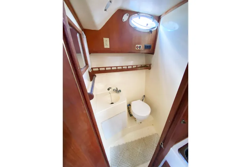 Slide: The Image of 1997 Albemarle 30 Express boat bathroom with sink, toilet, and porthole window. - 32