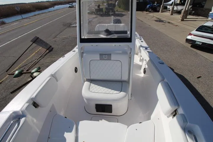 Slide: The Image of 2026 Sea Fox 228 Commander boat interior with white seating and console, parked near a road. - 6