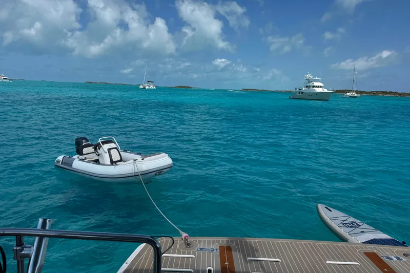 Slide: The Image of A 2021 Leopard 53 Powercat with dinghy and paddleboard in turquoise waters. - 11