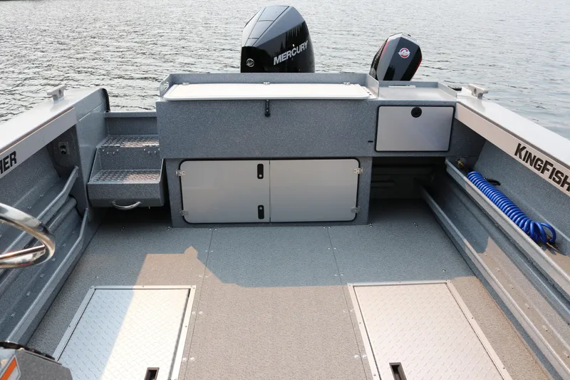 Slide: The Image of 2026 KingFisher 2425 Escape HT boat interior with storage compartments and Mercury engine on water. - 24