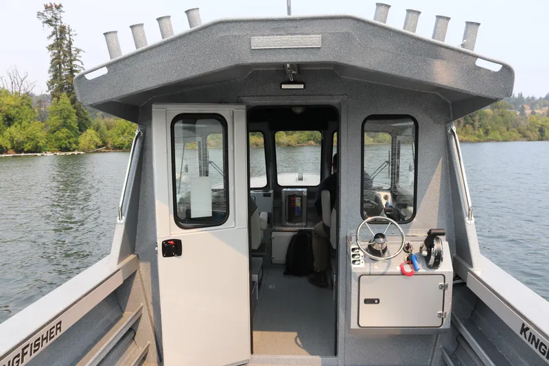 Slide: The Image of 2026 KingFisher 2425 Escape HT boat on water, showcasing cabin interior and steering console. - 3