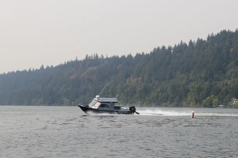 Slide: The Image of 2026 KingFisher 2425 Escape HT boat cruising on a scenic lake with forested hills. - 36