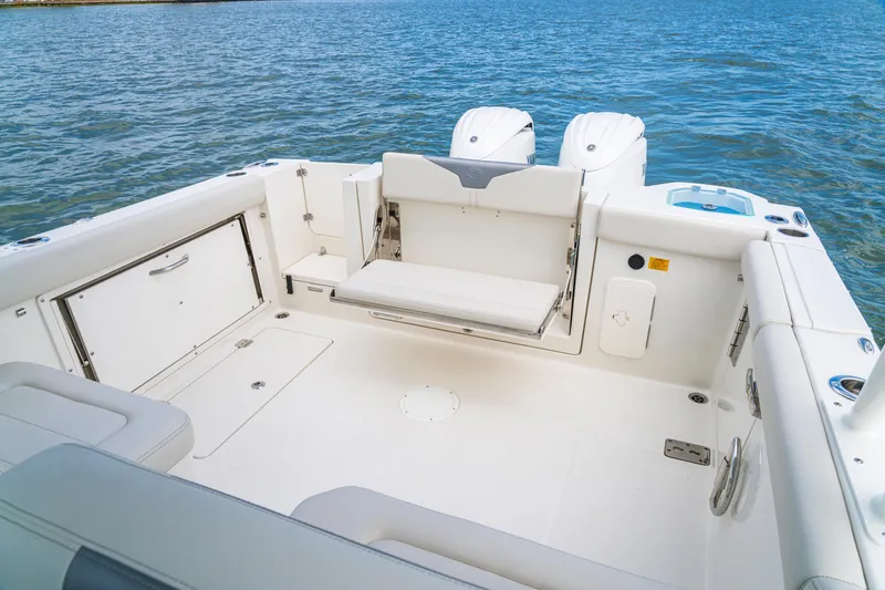 Slide: The Image of 2027 Sailfish 276 DC boat interior with seating, storage, and twin engines on a calm sea. - 21