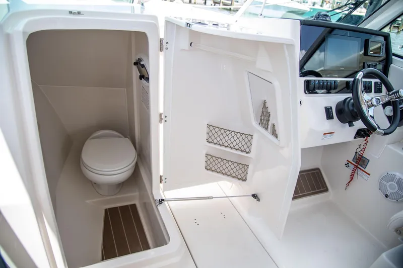Slide: The Image of 2027 Sailfish 276 DC boat interior with helm and compact marine toilet. - 8
