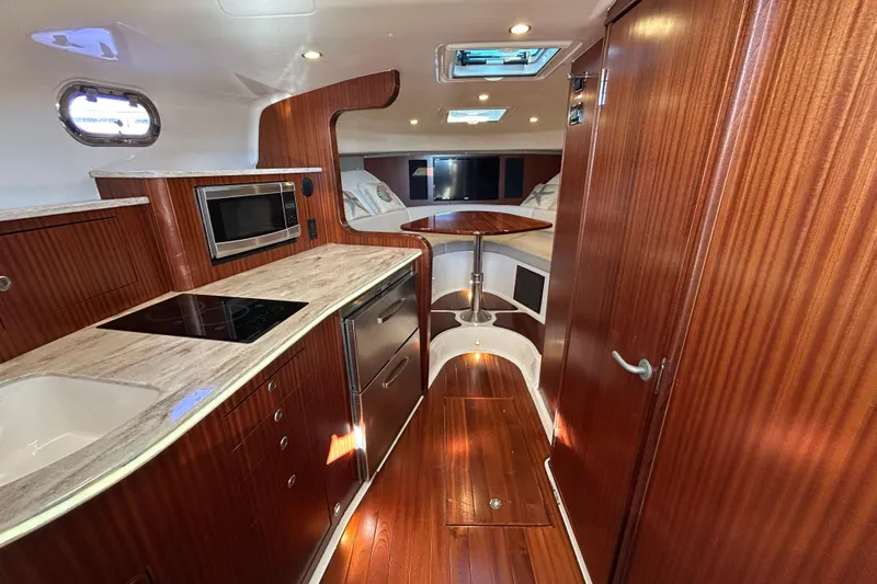 Slide: The Image of 2018 Pursuit OS 385 Offshore interior with wood finish, kitchenette, and dining area. - 14