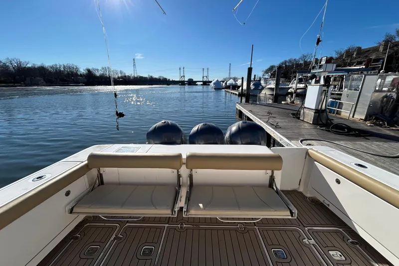 Slide: The Image of 2018 Pursuit OS 385 Offshore boat docked, featuring spacious seating and triple outboard engines. - 3