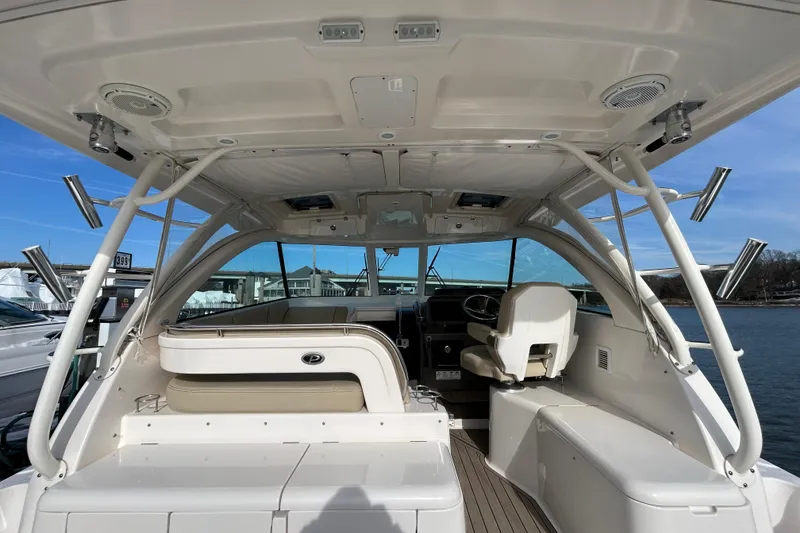 Slide: The Image of 2018 Pursuit OS 385 Offshore boat interior with seating and helm, docked by the water. - 6