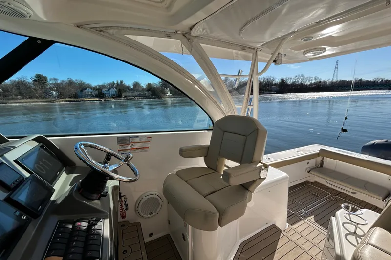 Slide: The Image of 2018 Pursuit OS 385 Offshore boat interior with helm and seating, overlooking calm waters. - 9