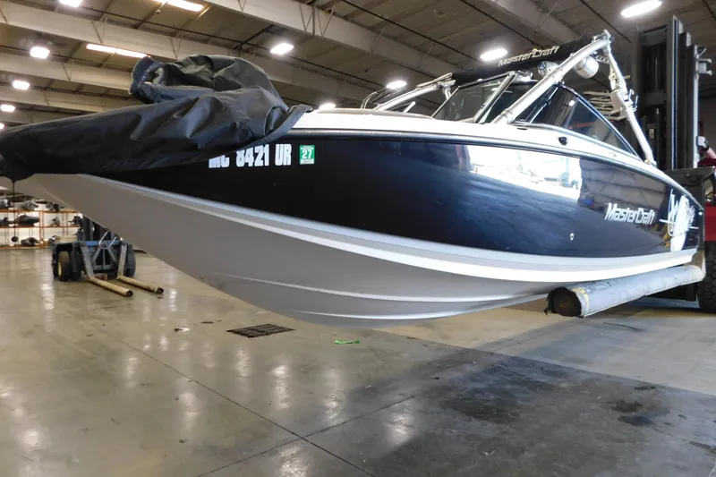 Slide: The Image of 2009 MasterCraft X55 boat in a warehouse, partially covered, elevated on a lift. - 16