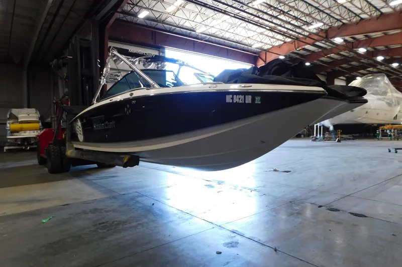 Slide: The Image of 2009 MasterCraft X55 boat in warehouse, lifted by forklift for maintenance. - 7