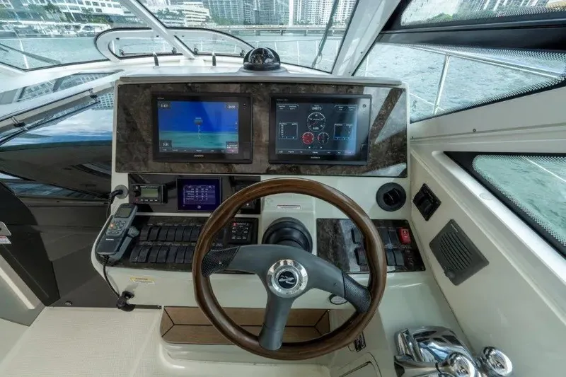 Slide: The Image of 2009 Sea Ray 43 Sundancer helm with dual displays and wooden steering wheel. - 52