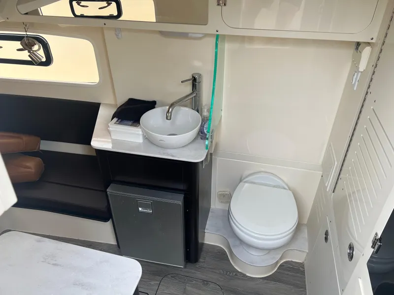 Slide: The Image of 2019 Scout 355 LXF boat interior with sink, toilet, seating, and mini fridge. - 17