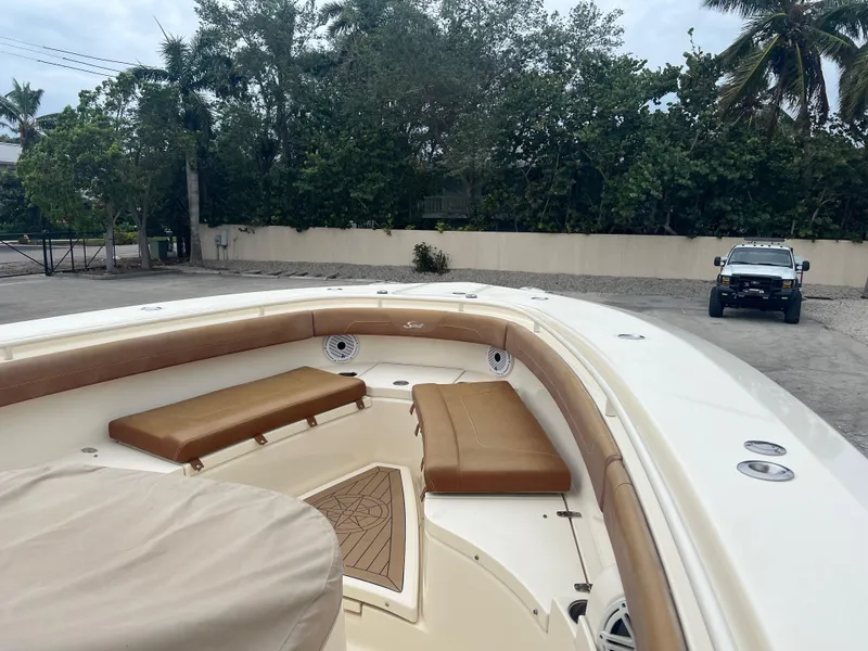 Slide: The Image of 2019 Scout 355 LXF boat with tan seating, parked outdoors. - 19
