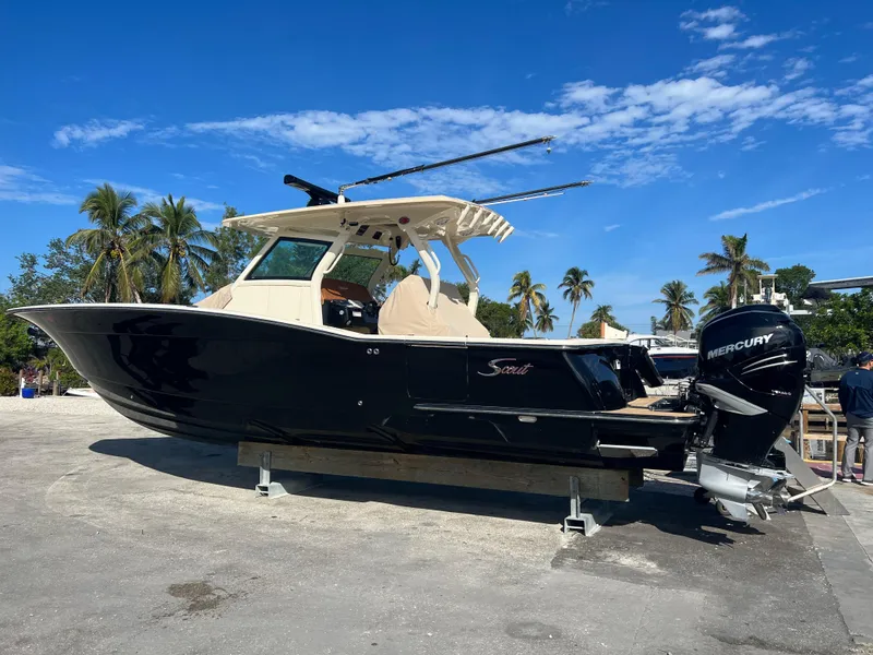 Slide: The Image of 2019 Scout 355 LXF boat with Mercury engines, parked on a sunny day. - 2
