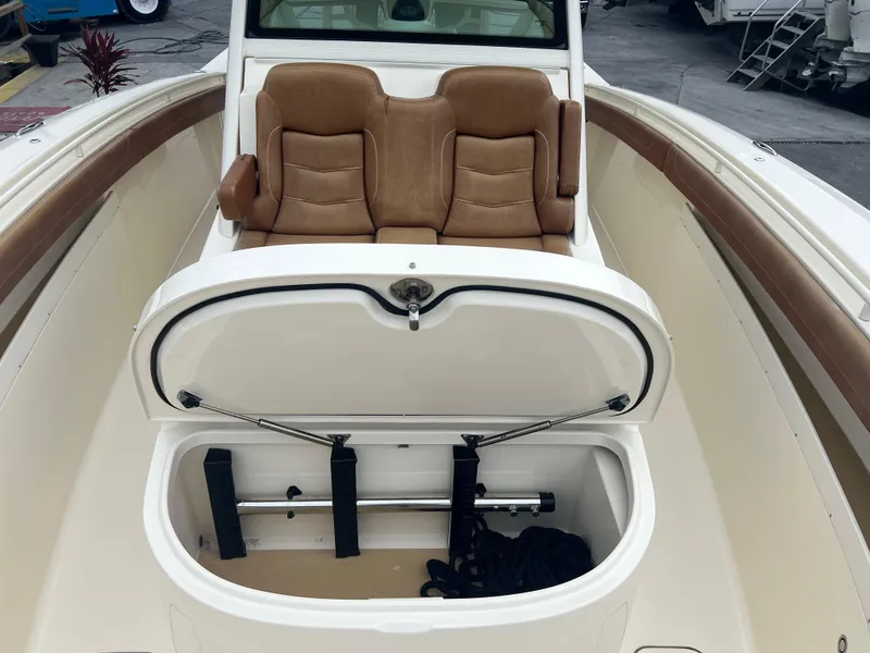 Slide: The Image of 2019 Scout 355 LXF boat with open storage compartment and tan leather seats. - 21