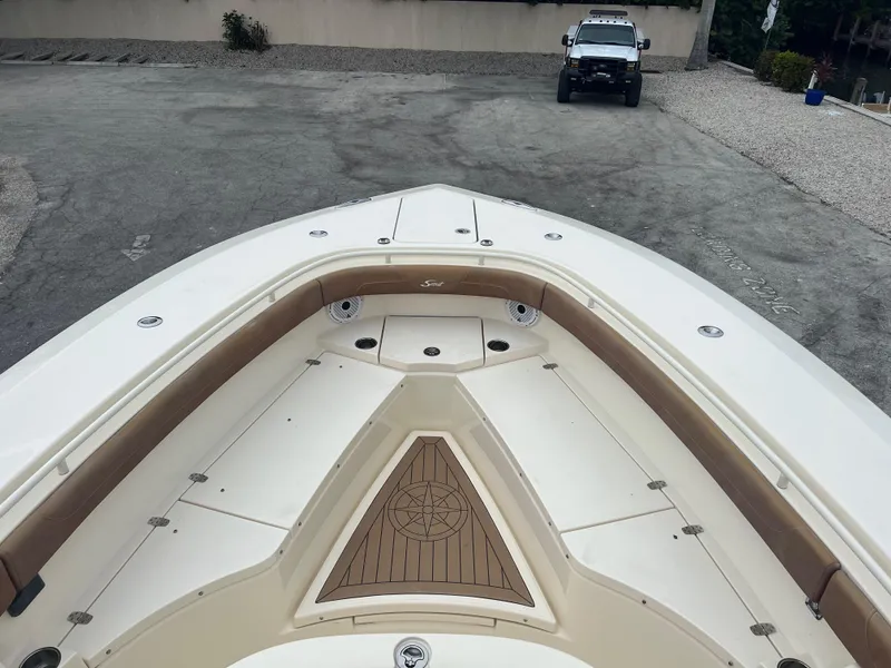 Slide: The Image of 2019 Scout 355 LXF boat bow with seating, parked on concrete. - 23