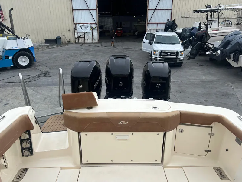 Slide: The Image of 2019 Scout 355 LXF boat with triple outboard engines in a marina setting. - 8