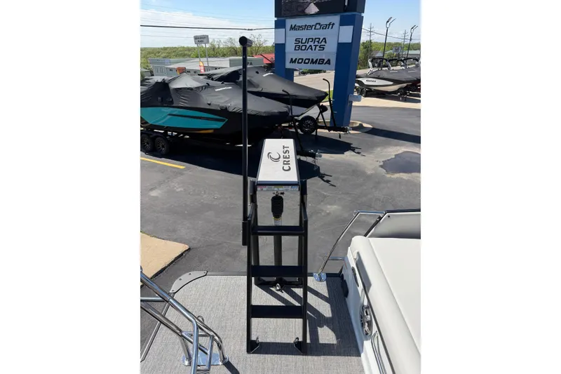 Slide: The Image of 2026 Crest Caribbean 250 SLS boat ladder at a dealership with covered boats in background. - 45