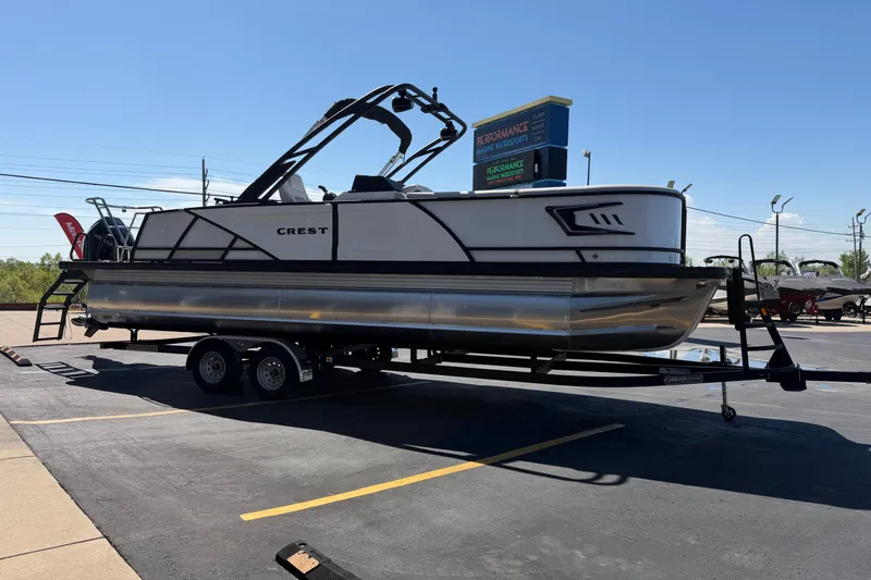 Slide: The Image of 2026 Crest Caribbean 250 SLS pontoon boat on trailer in parking lot. - 9