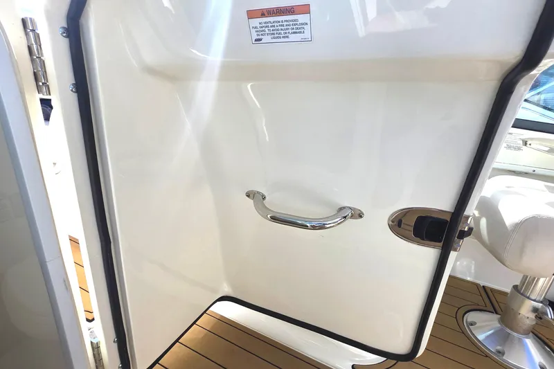 Slide: The Image of 2015 Boston Whaler 270 Vantage cabin door with chrome handle and teak flooring. - 13