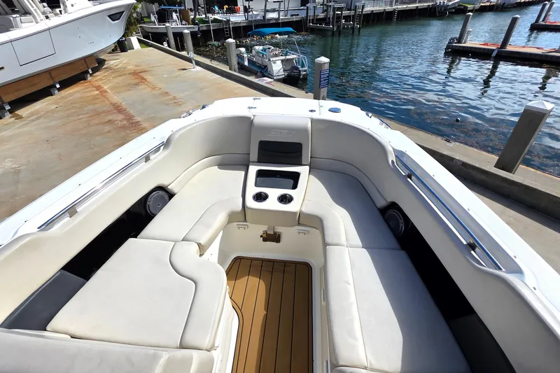 Slide: The Image of 2015 Boston Whaler 270 Vantage boat interior with cushioned seating at a marina. - 15