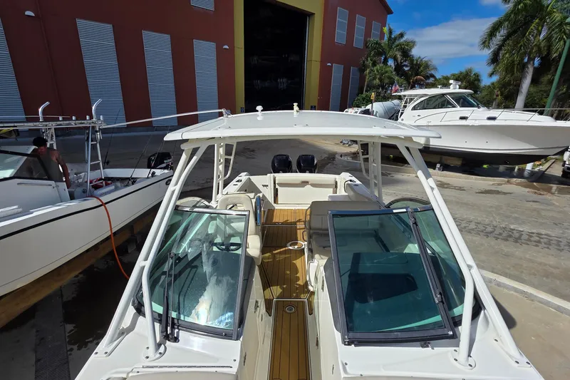 Slide: The Image of 2015 Boston Whaler 270 Vantage boat docked near a marina with palm trees. - 58