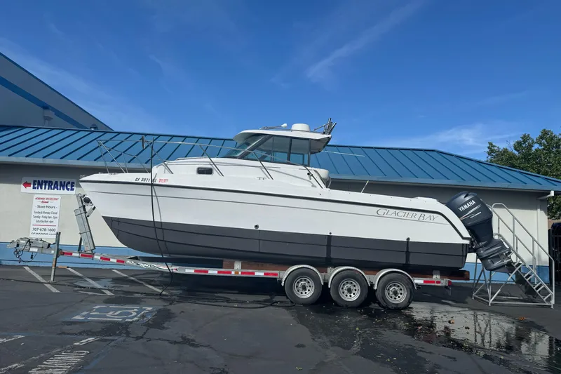 The Image of 2000 Glacier Bay 2680 Coastal Runner boat on trailer, parked outside a building. - 1