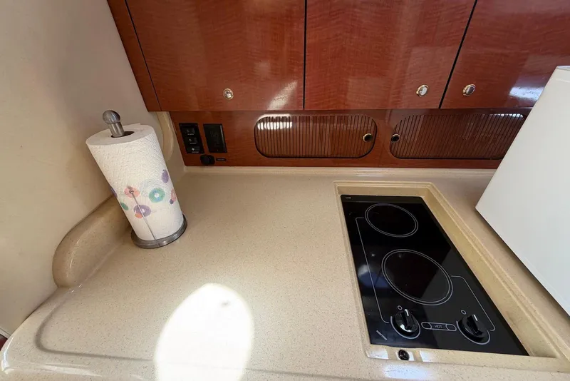 Slide: The Image of 2003 Sea Ray 340 Sundancer galley with stove, cabinets, and paper towel holder. - 19