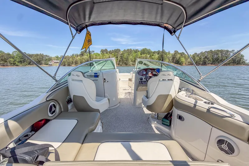 Slide: The Image of 2007 Sea Ray 220 Sundeck interior with seating, steering wheel, and canopy on a lake. - 16