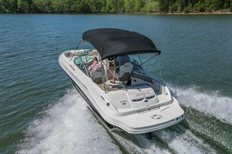 Slide: The Image of 2007 Sea Ray 220 Sundeck cruising on a serene lake with lush green shoreline. - 5
