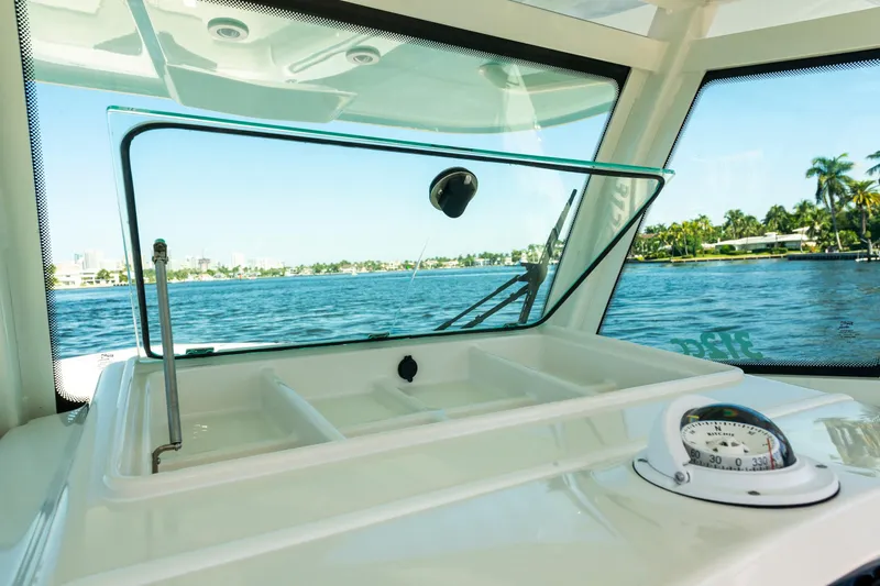 Slide: The Image of 2027 Sailfish 312 CC boat interior with open hatch and compass, overlooking serene water. - 11