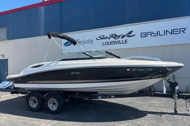 The Image of 2012 Sea Ray 210 SLX boat on trailer at dealership, Louisville signage in background. - 1