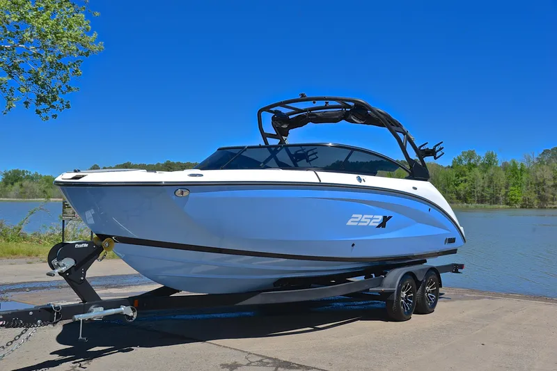Slide: The Image of 2024 Yamaha Boats 252XE on trailer by a lake under clear blue sky. - 10