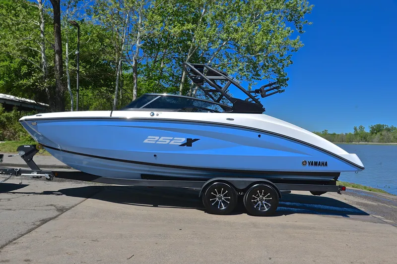 Slide: The Image of 2024 Yamaha Boats 252XE on trailer by a lake, surrounded by trees. - 11