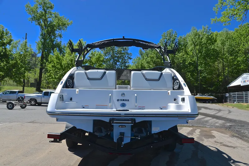 Slide: The Image of 2024 Yamaha Boats 252XE on trailer, rear view, outdoors with trees in background. - 13