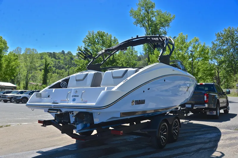 Slide: The Image of 2024 Yamaha Boats 252XE on trailer, parked outdoors with trees in the background. - 14