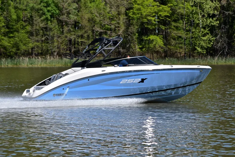 Slide: The Image of 2024 Yamaha Boats 252XE cruising on a serene lake with lush green forest backdrop. - 3