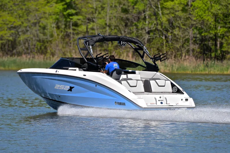 Slide: The Image of 2024 Yamaha Boats 252XE cruising on a lake with lush green trees in the background. - 4