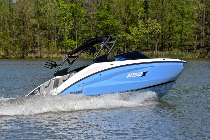 Slide: The Image of 2024 Yamaha Boats 252XE cruising on a lake with lush green trees in the background. - 5