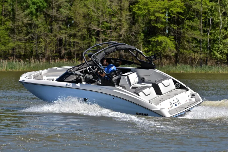 Slide: The Image of 2024 Yamaha Boats 252XE cruising on a lake with lush green trees in the background. - 6