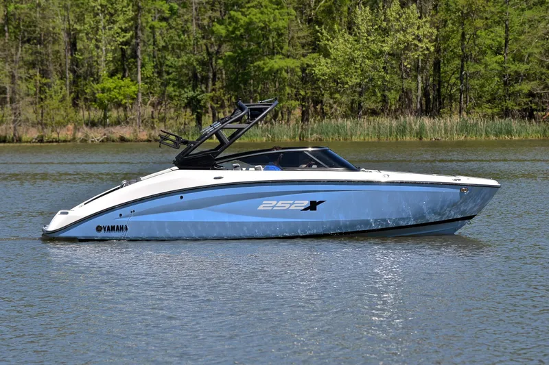 Slide: The Image of 2024 Yamaha Boats 252XE on a serene lake with lush green trees. - 7