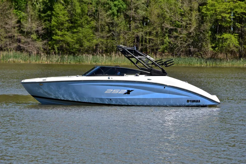 Slide: The Image of 2024 Yamaha Boats 252XE on a serene lake with lush green trees. - 9