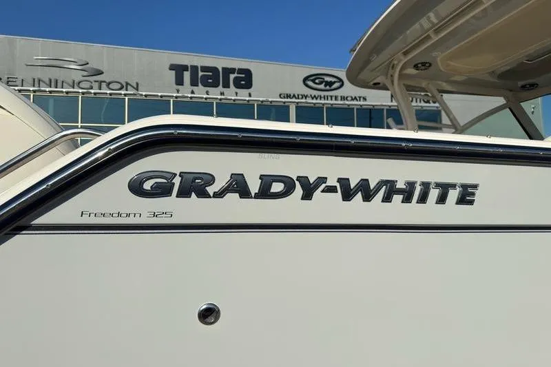 Slide: The Image of 2025 Grady-White Freedom 325 boat exterior with logo and dealership background. - 20