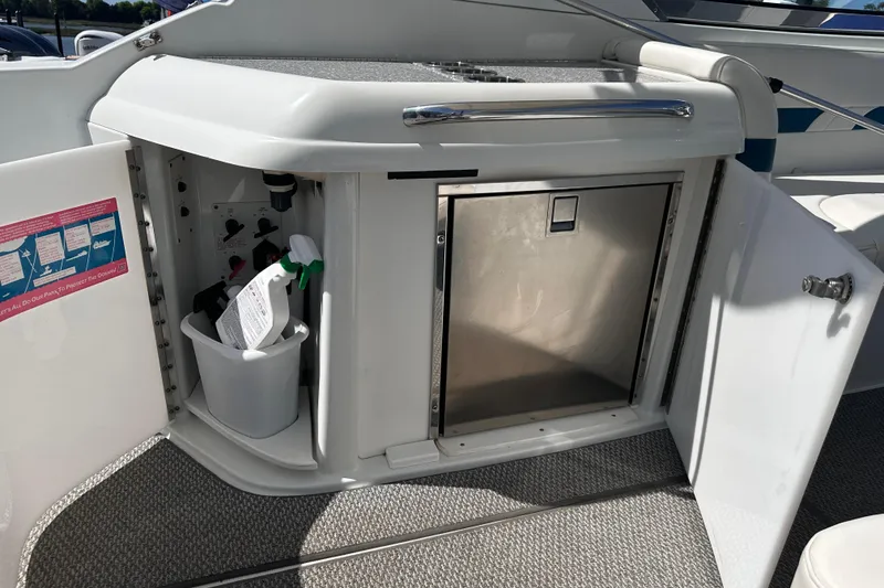 Slide: The Image of Open storage compartment on a 2006 Formula 280 Bowrider boat, featuring cleaning supplies. - 9